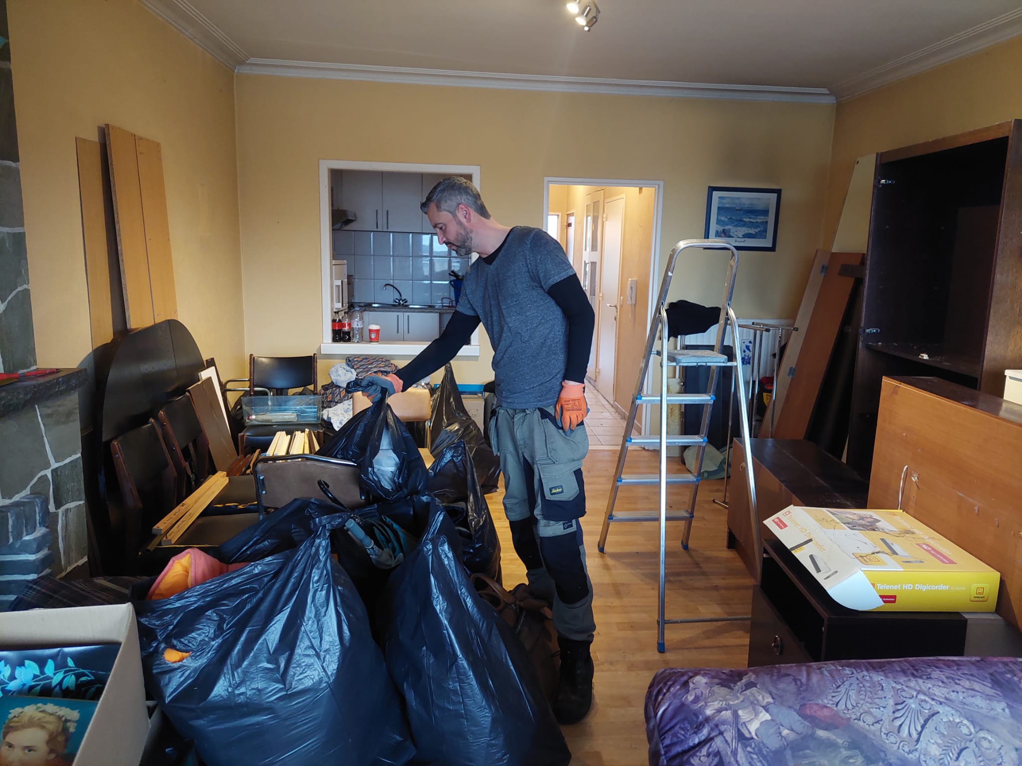 Medewerker van Huisopruimers sorteert meubels en vuilniszakken tijdens het leegmaken van een woning