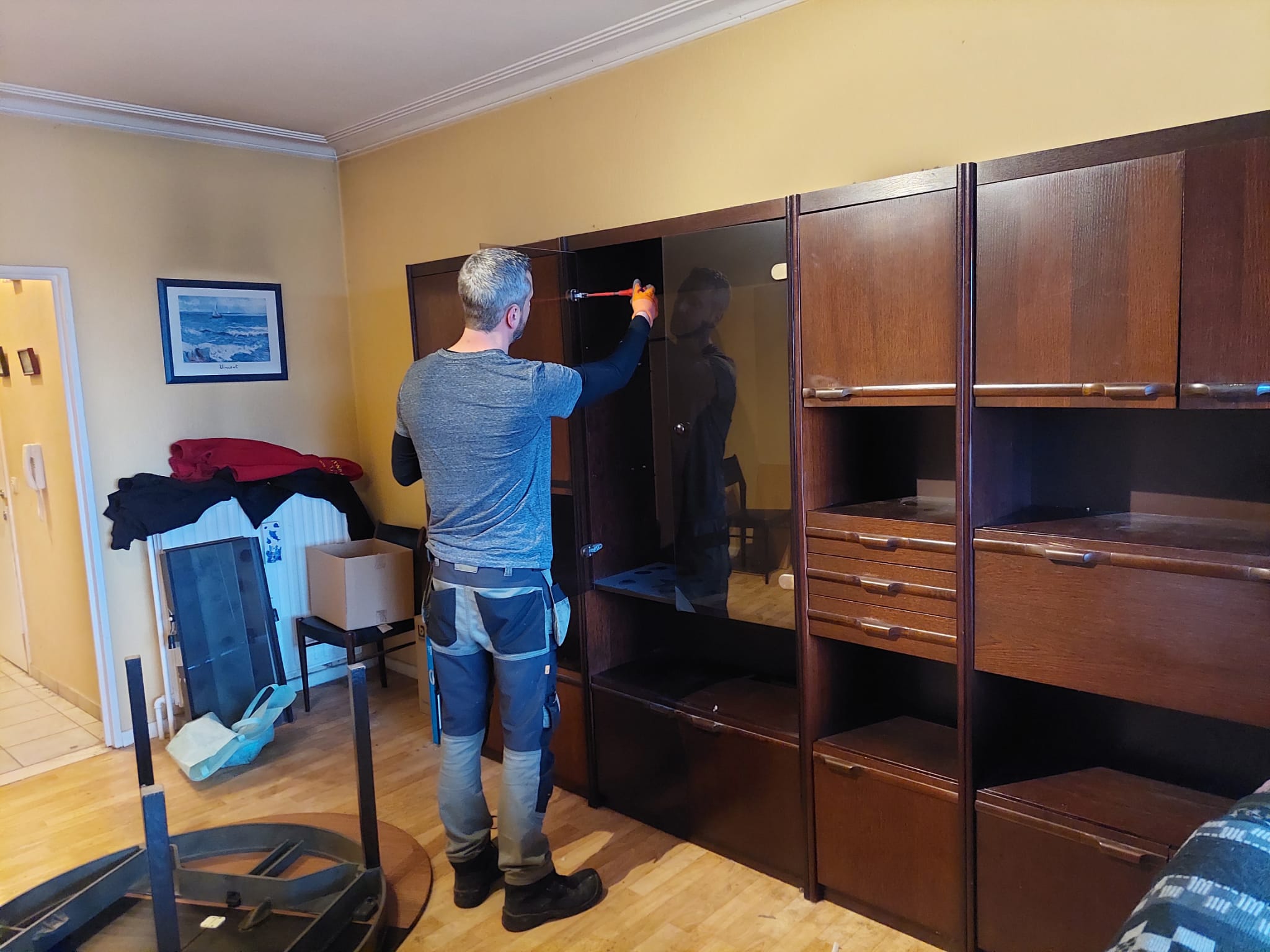 Medewerker van Huisopruimers demonteert een houten wandkast tijdens het leegmaken van een huis